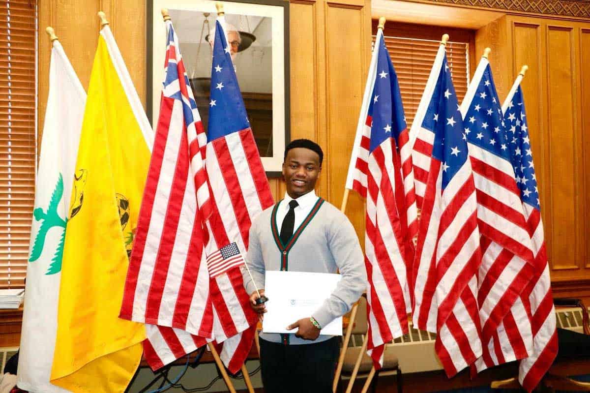 Wilson Kubwayo in front of flags at his citizenship ceremony