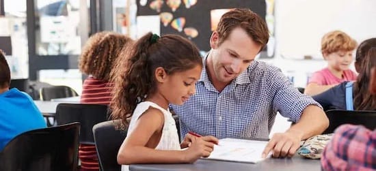 male teacher helping child in classroom
