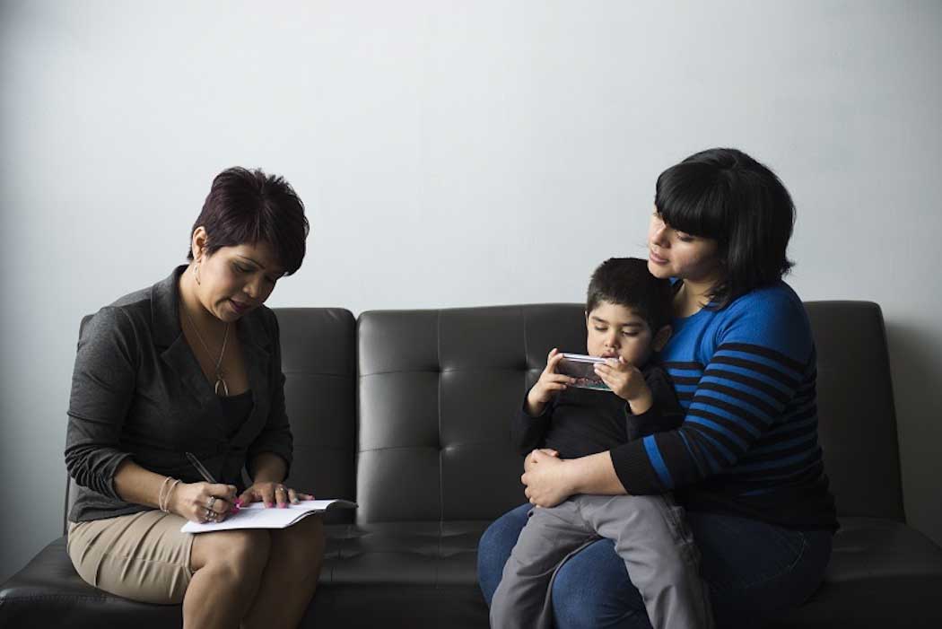 mother and small child on sofa with adviser taking notes