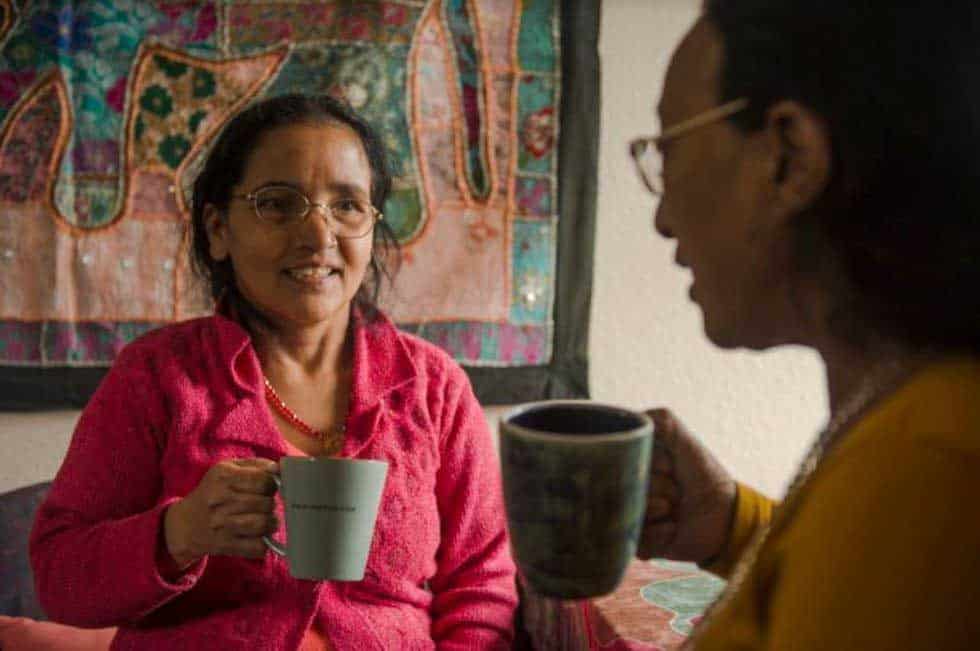 older women with cup at home talking to companion