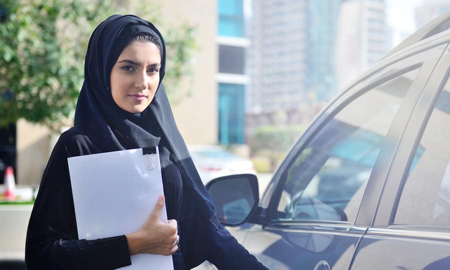 woman in black with papers by car