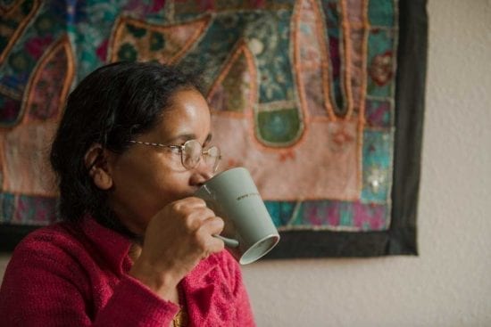 woman wearing glasses drinking from a cup