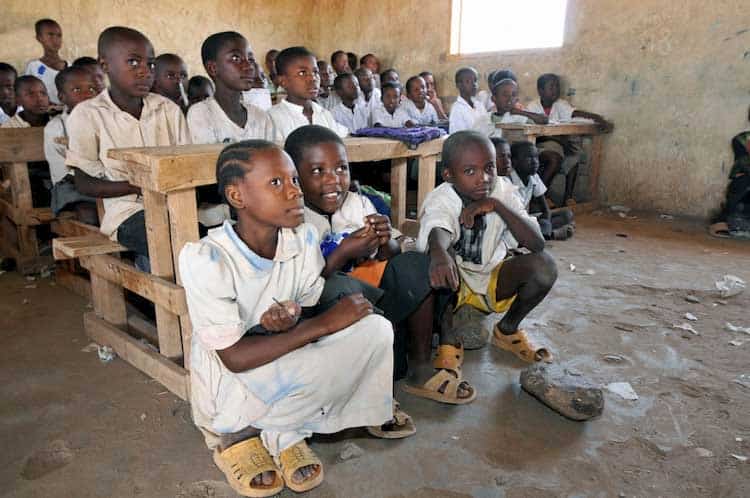 young children at school sitting on benches and rocks