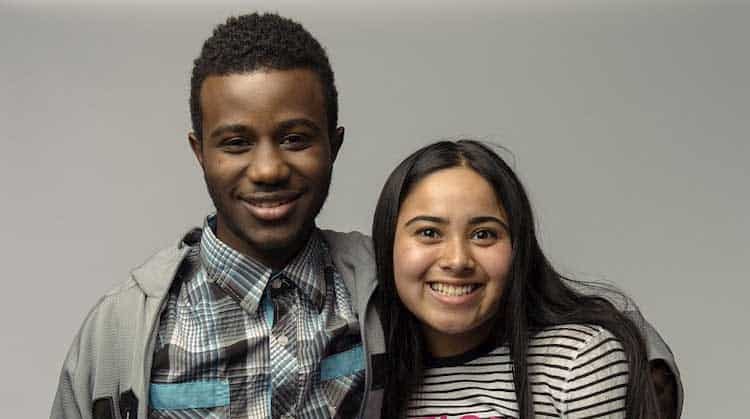 young man and woman side by side hugging and smiling at camera