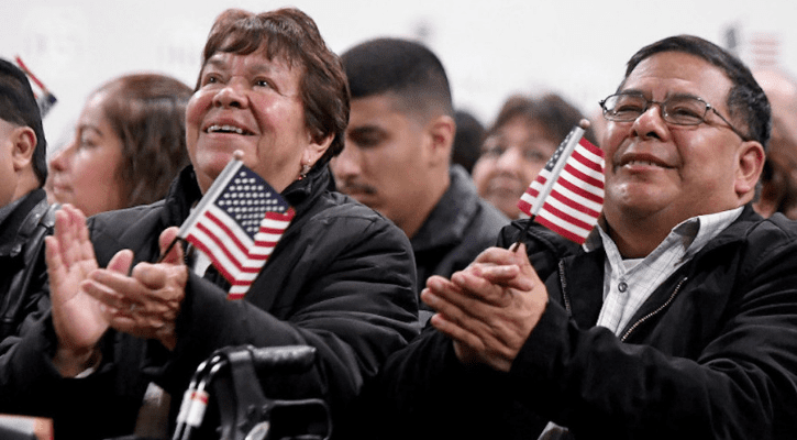 older woman with walker and map clapping at citizenship ceremony
