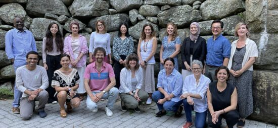 USAHello staff and board of directors standing and crouching together in front of a rock wall