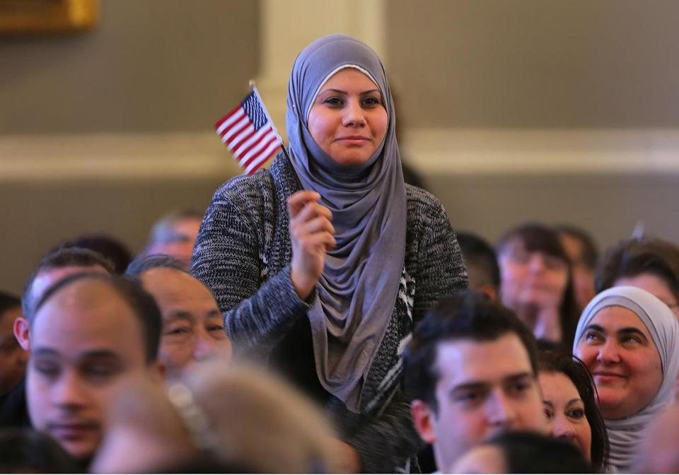 muslim woman holding flag at naturalization ceremony